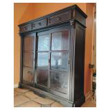 Ashley Furniture Rowley Creek Cabinet/ Hutch, Black rubbed finish, 3 drawers across top, glass front two doors on ends slide open, 64 1/4"T x 64"W x 19 1/2D, 2 glass shelves. BUYER IS RESPONSIBLE FOR 
