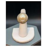 Silver tone ring with large pearl-like bead surrounded by clear stones…..size 7