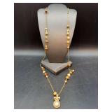 Long gold tone link chain necklace with beaded enhancements and teardrop pearl-like pendant and rhinestone bow