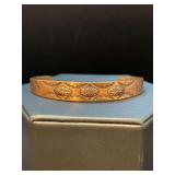 Hand-forged copper cuff bracelet with stamped designs, possibly in a traditional Native American style