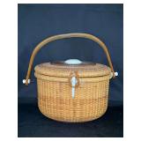 Nantucket lightship basket purse, featuring traditional rattan cane weaving, a solid wooden base, a hinged lid, and a wooden handle…..left side of handle needs repair and piece to attach hand is ins