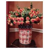 Southwest-style plastic decorative vase featuring a checkerboard pattern with Kokopelli figures, filled with an arrangement of artificial pink rose flowers. 19' T, 16' across flowers. Other contents n