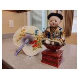 Vintage collectible Japanese Ichimatsu doll,  from the early to mid-20th century,  gofun finish (a white pigment made from oyster shells) on its face. Vintage Haeger pottery red pedestal  candle (doll