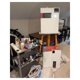 A wooden easel 24“ x 62“, three unopened canvases and aluminum three shelf rolling cart that is 27“ x 16“ x 31 1/2“, and miscellaneous art supplies to include paint and brushes as shown