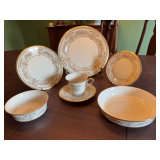 Seven piece Lenox Gold trimmed place setting. Castle Garden pattern.  Set includes a 10 7/8 inch dinner plate, 8 inch salad plate, 6 1/2 inch dessert plate, 7 1/2 and 5 1/2 inch bowls and a cup and sa