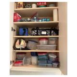 Kitchen cabinet with plasticware, casserole carrying case, lunch box and top two shelves of Christmas decor.