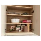 Cabinet of miscellaneous napkins, and cups with a large a 12 C Pyrex covered dish