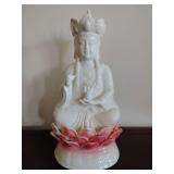 White porcelain statue of Guanyin, the Buddhist Bodhisattva of compassion, seated on a pink lotus base. 10" T.