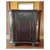 Hooker, Seven Seas kidney-shaped cabinet, distressed black finish with painted gold flourishes. 35 1/2" T x 36" W x 15" D. One center top drawer, one lower one shelf compartment middle, two side, one 