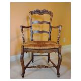 French provincial oak armchair with a hand-carved floral motif and a woven rush seat, Louis XV revival style. Back height 38", Seat height 17", Width 21 1/2". Good Condition, one broken rush strand se