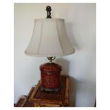 Vintage-style table lamp featuring a cinnabar red porcelain oval tea canister base with detailed gold floral motifs, set on a decorative brass base, and oval fabric shade. 20 1/2" T x 12" across botto