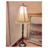 Chinoiserie style table lamp featuring a black lacquered finish with gold floral details. It stands on a hexagonal base, beaded fringe shade with two tassels. 31" T.