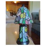 Small stained glass accent lamp in the style of Louis Comfort Tiffany, colorful floral mosaic design on both the shade and the base. 9 1/2" T x 5" across bottom of shade