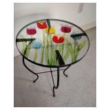 Small patio side table, black metal base, glass top  with a colorful tulip stained-glass design. 20" T x 14" across.