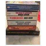Grouping of five Robert Ludlum paperback books and one hardcover book. See all photos.
