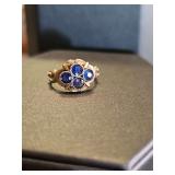 Unmarked gold tone ring with blue stones. Nonreactive to magnet. 1.93 grams. Size 4