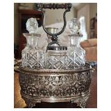 Silver plate cruet set with cut crystal bottles. Shaker bottle is cracked.