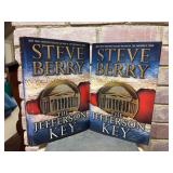 (2) Signed first edition hardback copies of “The Jefferson Key” by Steve Berry…..includes dust jackets and promo photo with only the book on the left, which also has staining on outer edges of p