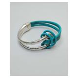 Multi-strand teal leather bracelet with a hammered silver-tone metal focal point and a magnetic clasp, combining colorful leather cords with textured, contemporary metal elements. With gift bag.