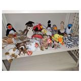 Shelf of TY beanie babies with hang tags and tush tags intact. Cats, unicorn, dragon, birds, and more.