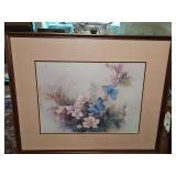 Framed pastel floral and blue butterfly art print features soft pink blossoms and delicate blue butterflies beneath layered peach matting. 33.5 x 27.5 in tall.