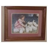 Framed print of a girl feeding bunnies. 23.5x19.5 in tall.