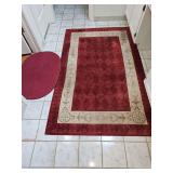 Burgundy and cream colored rug by Ashton house collection 66x42, and a burgundy braided rug 31x 20.5 in.