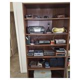 Contents of bookshelf. Bookshelf not included. Includes Sony boombox, Memorex boombox, wood look landline phone,vintage Bogen K030 public address amplifier from the late 1950s, 8-track player, VHS tap