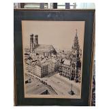 Framed black-and-white architectural lithograph print depicts an elevated perspective of Marienplatz and the Frauenkirche in Munich, Germany. Dated 1970. 18.5 x 23.5 in tall.