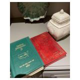 Group of decor pieces on shelf. 9” cracked oriental almond colored jar and 2 books