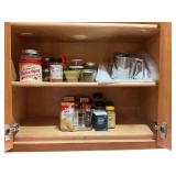 One drawer and cabinet full of spices and sifter.