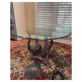 Exquisite vintage Hollywood Regency-style elephant base round glass top coffee table featuring four sculpted elephant heads with raised trunks forming the pedestal