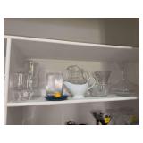 Shelf of various pieces of clear glass and plastic ware (wine glasses on far left are plastic)