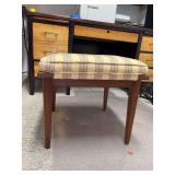 Vintage mid-century modern upholstered wooden stool features a striped yellow and green fabric cushion and tapered wooden legs