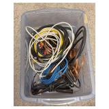 Clear plastic storage bin filled with an assortment of mixed electronic and audio-visual cables