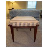 Vintage mid-century modern upholstered wooden stool features a striped yellow and green fabric cushion and tapered wooden legs