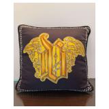 Versace 17” decorative throw pillow featuring a black or dark brown cover with a prominent gold Gothic-style monogram and Greek key border