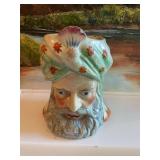 A ceramic tobacco jar in the form of a Turkish head. Has crazing and without lid. Has chip.