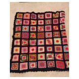 Child size vibrant handmade crocheted granny square throw blanket featuring colorful retro motifs joined together with a bold black border