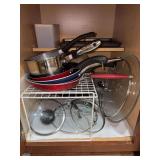 Contents of bottom kitchen cabinets (left and right of stove) and drawer under stove - misc. pots and pans, random lids, Copper Chef pot