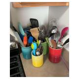 Set of  four multicolored Le Creuset utensil holders with utensils.