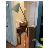 ￼ Adjustable, mid-century modern floor lamp featuring a slender brass frame with a beige light shade.