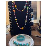 54 inch beaded necklace with two turquoise colored bracelets. One is a stretch bracelet and the other is a glass jeweled bracelet