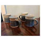 Set of four signed pottery coffee mugs.