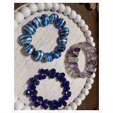 Three beaded stretch bracelets, two blue and one purple and white