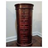 Hives & Honey Daley oval standing jewelry armoire in a rich cherry finish, mirrored flip up lid with seven stacked pull-out drawers and concealed side doors. 39.5"T x 18"W x 14"D. Contents not include
