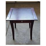 Wood side table with one drawer and tapered legs. Laminate table top needs refinished or repaired. 19.75 x 19.75 x 20.25 in tall.