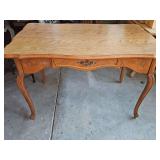 French Provincial / Louis XV style writing desk or vanity table featuring a honey oak finish, cabriole legs, and carved floral detailing along the apron and drawer. 48 x 30 x 30.5 in tall. Some sticke