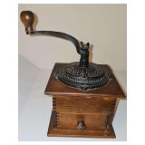 Antique wooden box coffee grinder featuring a black cast-iron hand-crank top and a small pull-out drawer. Likely manufactured between late 1800s and very early 1900s.