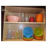 Two shelves of glassware. Blue Harbor covered casserole dish, three orange soup bowls, beverage glasses and coffee mugs, seven swirl beverage glasses, eight bowls, 10 sandwich/dessert plates,